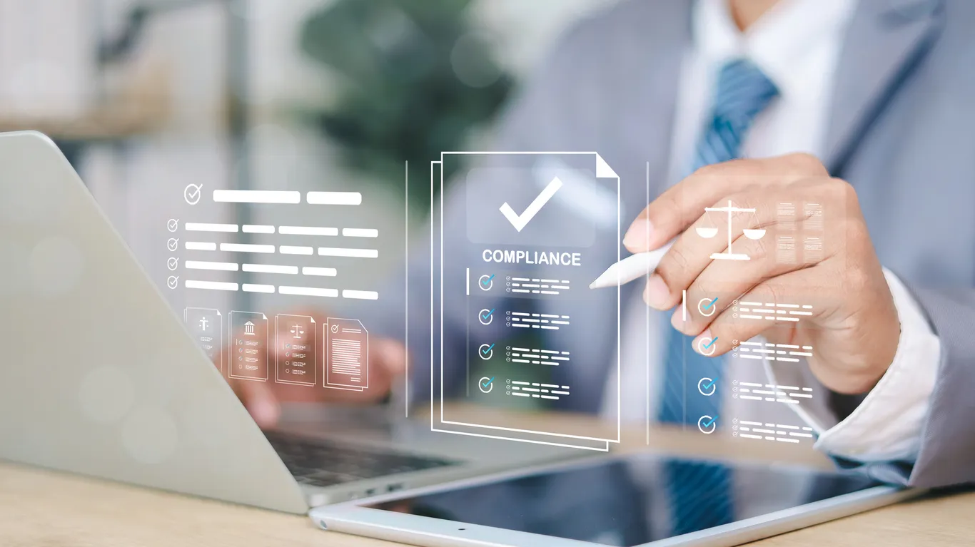 Compliance checklist and laptop on an office desk