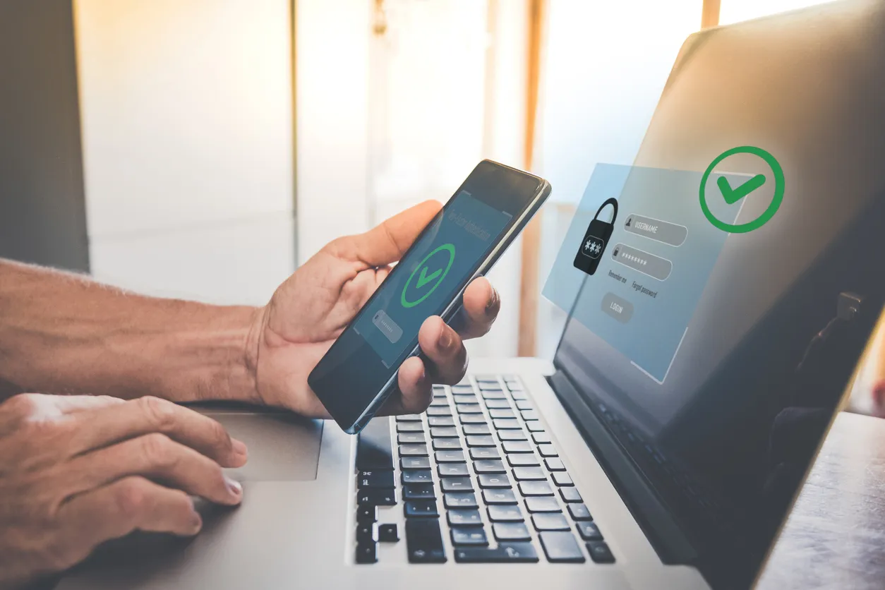 Smartphone showing an authenticator app approval prompt next to a laptop on a desk