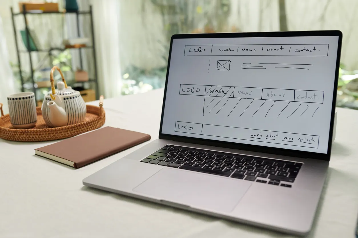 Desk with a project timeline sketch, a laptop showing a website draft, and a calendar.