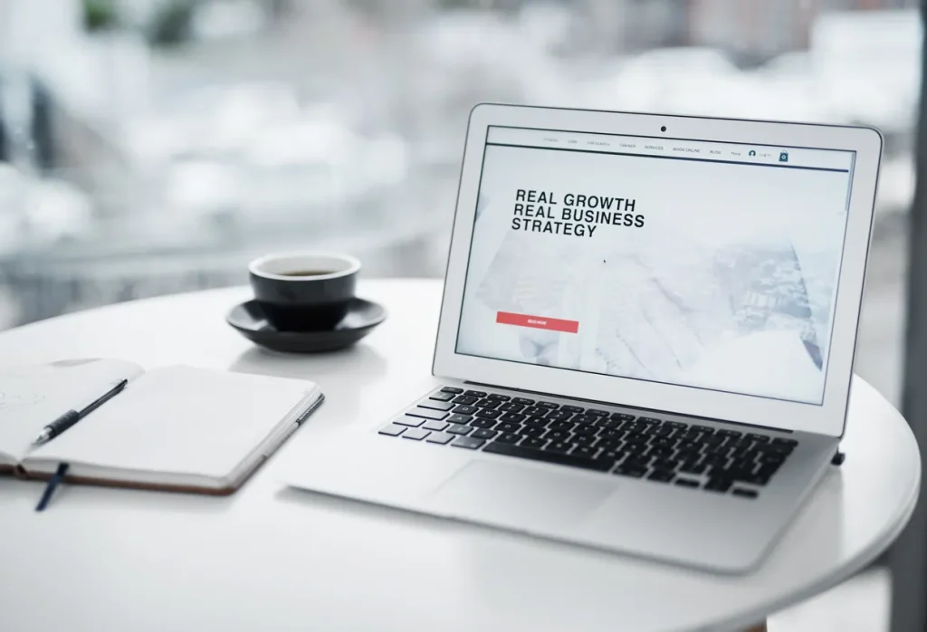Laptop screen showing a single focused landing page with one call-to-action button, on a tidy desk