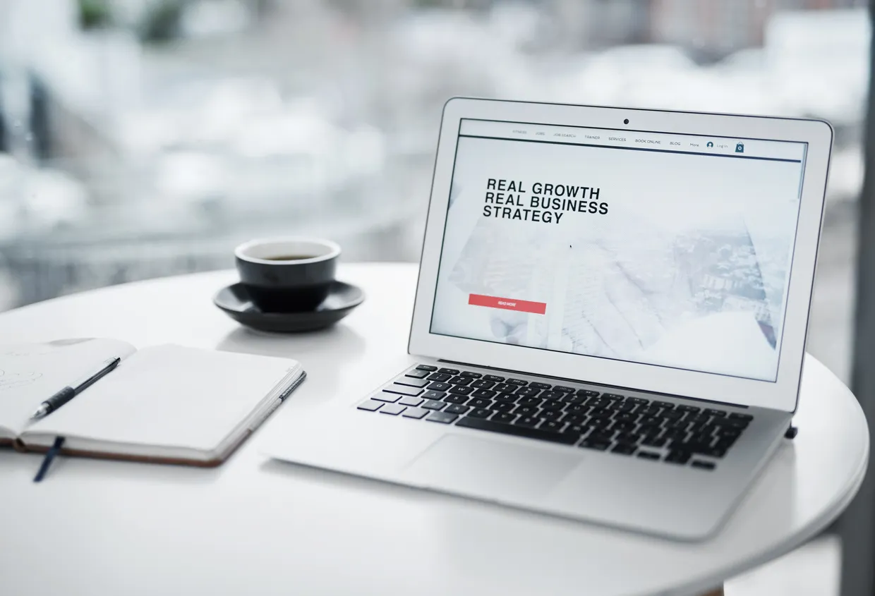 Laptop screen showing a single focused landing page with one call-to-action button, on a tidy desk.