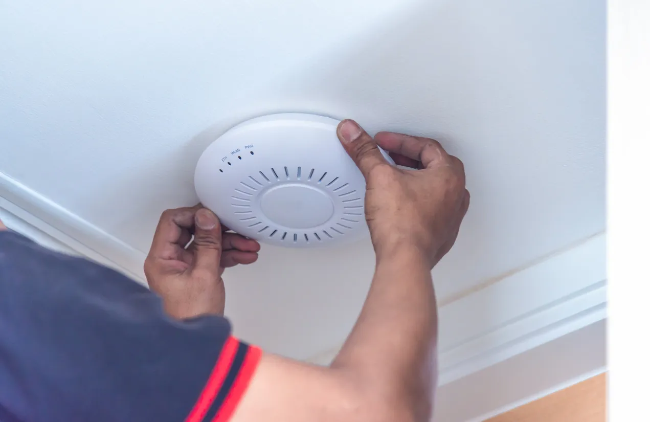 UniFi access point mounted on an office ceiling with status LED visible.