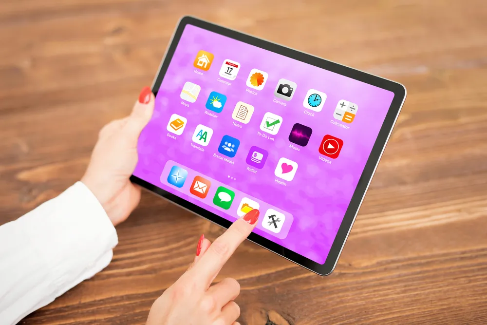 iPad on a desk showing a grid of application icons