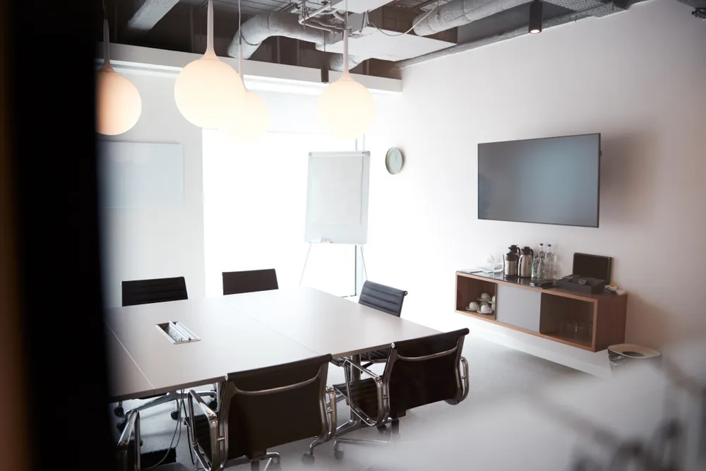 Meeting room with a screen and empty chairs around a table