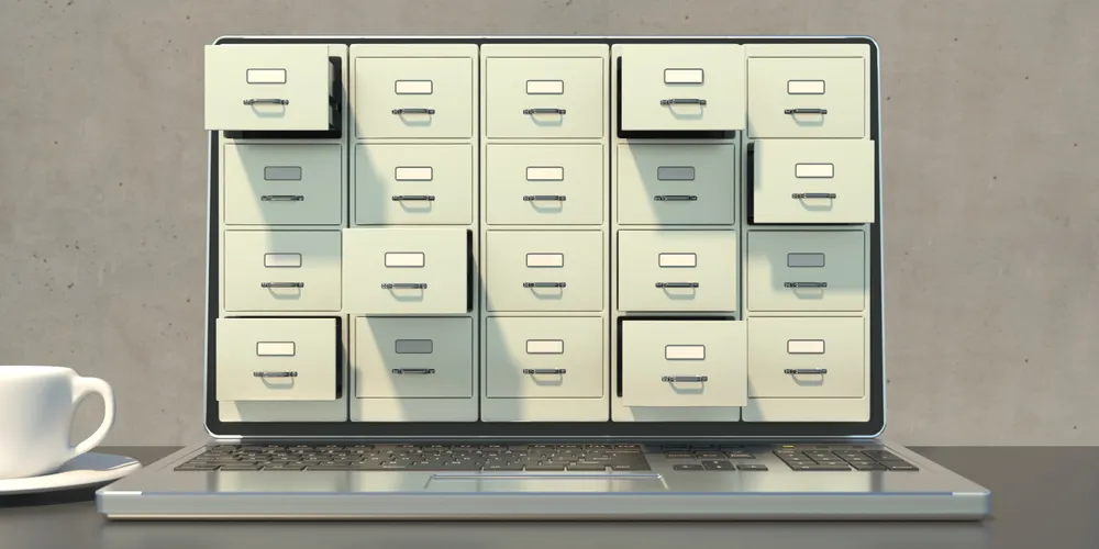 Filing cabinet drawer open beside a laptop on a desk