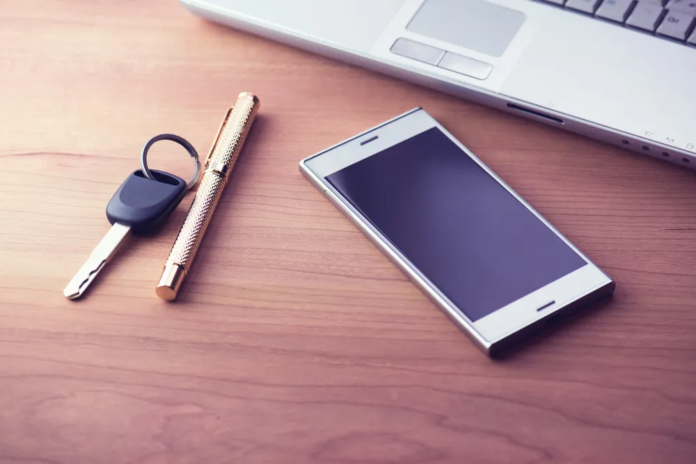 Hardware security key and a mobile phone showing an authenticator app on a desk