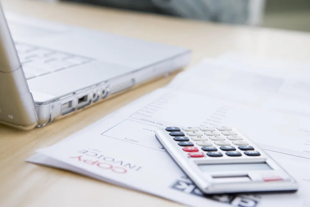 Invoice paperwork and a calculator on an office desk