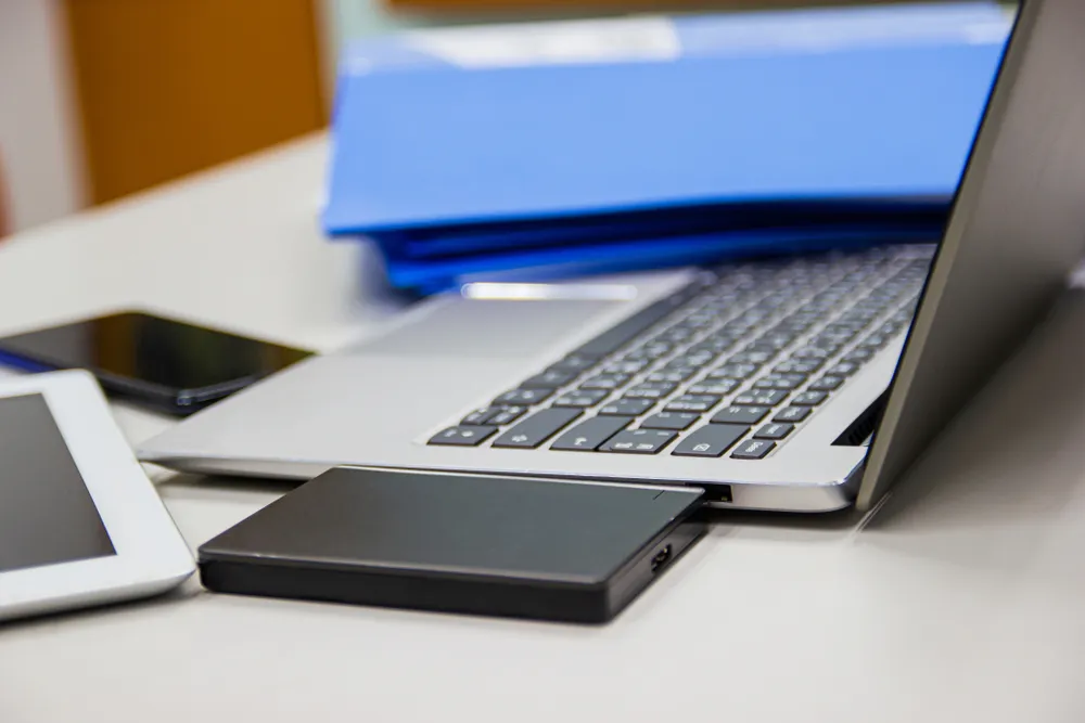Office laptop and external drive on a desk, representing files leaving a business network.