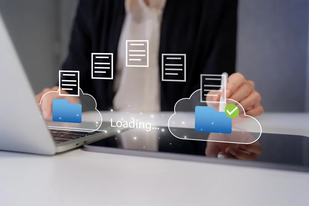 Laptop showing cloud sync icons on a desk in an office.