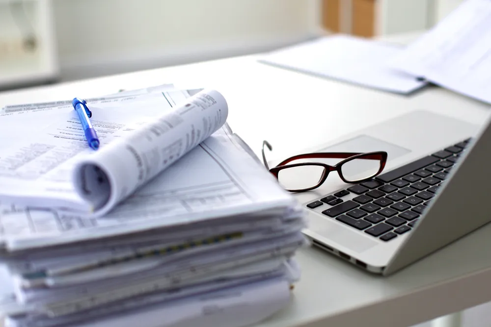 Office desk with printed documents and a laptop.