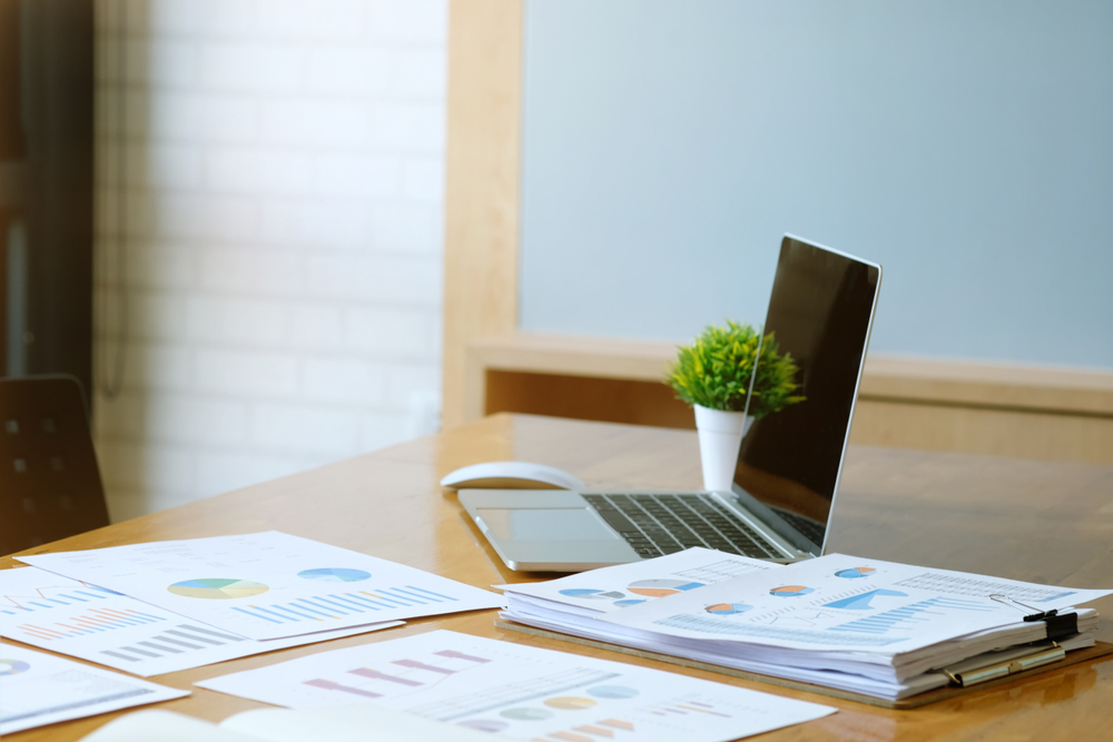Printed documents and a laptop on an office desk.